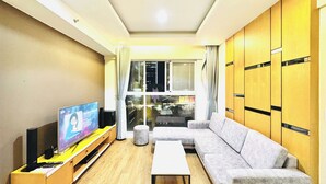 Una sala de estar con sofá, mesa de centro, televisor y ventana con cortinas.