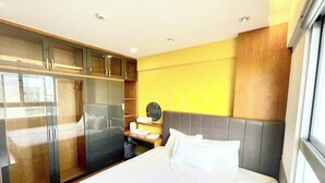Una habitación de hotel con cama, armario, mesita de noche y espejo.