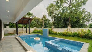 A swimming pool with tiled steps, a covered area, and a surrounding garden. - Elivaas Casa Verdea 4BHK Villa With Pool (Siolim)