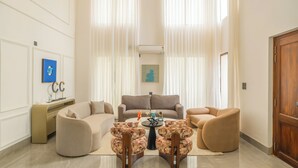 A modern living room with a beige sofa, two armchairs, a coffee table, and a sideboard. - Elivaas Casa Verdea 4BHK Villa With Pool (Siolim)