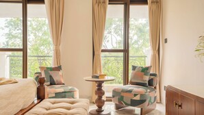 A bedroom with a bed, a chair, a small table, and a cabinet. - Elivaas Casa Verdea 4BHK Villa With Pool (Siolim)