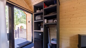 A compact kitchen with a refrigerator, shelves, and a trash bin. - Glamping at Four Fillies Lodge-The Little John (Peterstown)