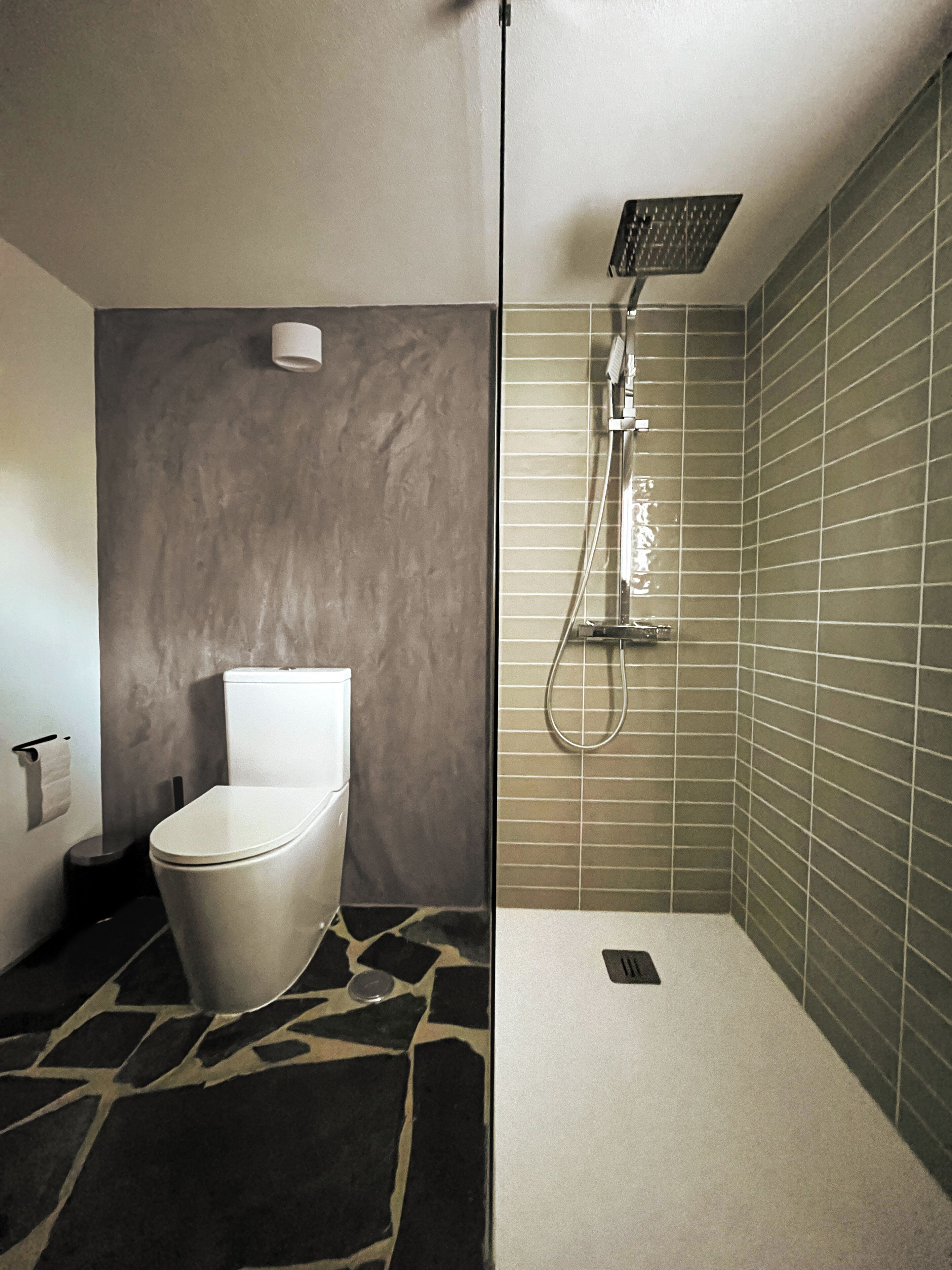 Un bagno moderno con il water, una doccia e un pavimento piastrellato.