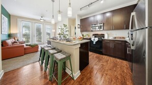 A modern kitchen with dark cabinets, stainless steel appliances, and a central island with stools.