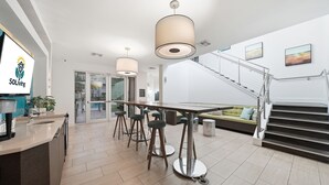 A modern kitchen with a bar area, a staircase, and a dining area.