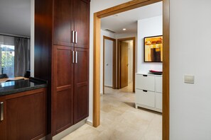 Eine moderne Küche mit Holzschränken, einer Arbeitsplatte und einem Gang zu einem Badezimmer mit Spiegel und Waschbecken.