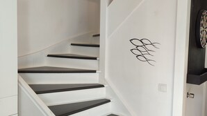 A white staircase with black steps, a door with a decorative design, and a dartboard on the wall. - Cosy and quiet house between Landes and Pays Basque (Tarnos)