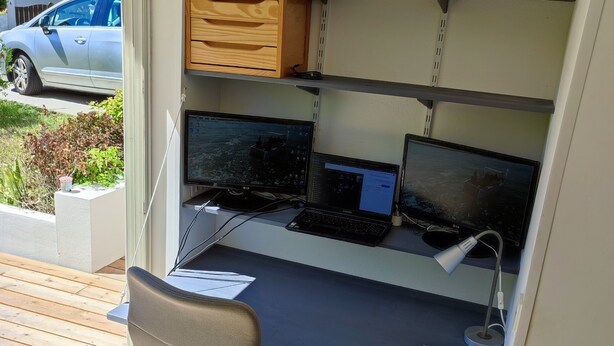 A compact office space with a desk, two monitors, a chair, and shelves. - Cosy and quiet house between Landes and Pays Basque (Tarnos)