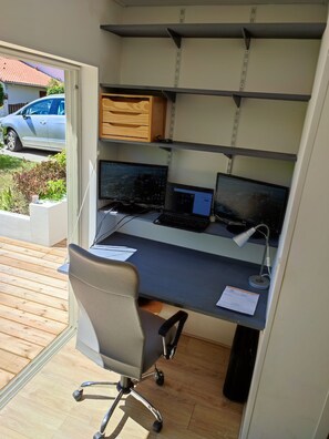 Ett kompakt kontorsutrymme med ett skrivbord, två datorskärmar, en stol och hyllor.