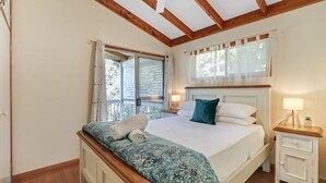 A bedroom with a bed, bedside tables, a window with curtains, and a balcony.