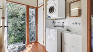 A compact laundry room with a front-loading washer and dryer, a small sink, and a mirror above the dryer.