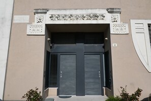 A building entrance with a large double door, a small window with shutters, and a decorative stone frame above the door. - SE231 – Senigallia, renovated apartment with a/c (Senigallia)