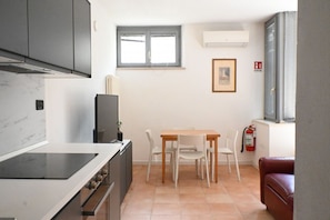 A compact kitchen with a dining area, a window, and a fire extinguisher.