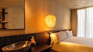 A modern hotel room with a large bed, a stone basin, a wall-mounted lamp, and a mirror. - chic&basic Tokyo Hoose (Porto)