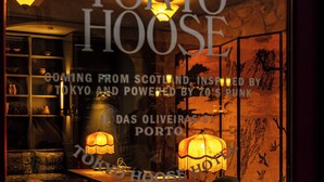 A cozy interior with a table, chairs, and a lamp. Text on the window indicates the name 'Tokyo House' and mentions 'Scotland' and '70's Punk'. - chic&basic Tokyo Hoose (Porto)