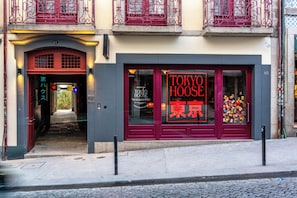 En bygning med rødt entreparti og et stort vindue, der viser 'TOKYO HOUSE' og '東京' med røde bogstaver.