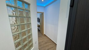 En gang med glasdør, trægulv og loft med blå belysning.
