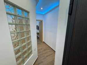 A hallway with a glass door, wooden flooring, and a ceiling with blue lighting. - Spacious 2BR | 160m Metro | 3 min to Piraeus Port | 6 Guests (Nikea)