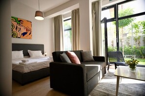 A modern hotel room with a bed, sofa, and a dining table. - Connect Living Serviced Apartments (Sofia)