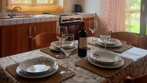 Una cocina con ventana, estufa y una mesa de comedor dispuesta con platos y copas de vino.