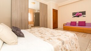 Un dormitorio con cama, sofá, espejo y puerta.