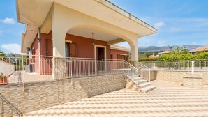 Un edificio con un patio cubierto, una escalera y vistas del paisaje circundante.
