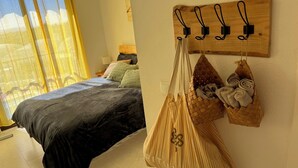 A bedroom with a bed, a hanging bag, and a wall-mounted towel rack. - Comfortable apartment with balcony and huge pool (Sucina)