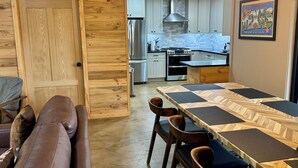 Una cocina moderna con armarios de madera, horno empotrado y comedor con mesa y sillas de madera.