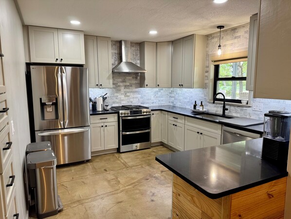 A modern kitchen with stainless steel appliances, white cabinetry, and a large island.