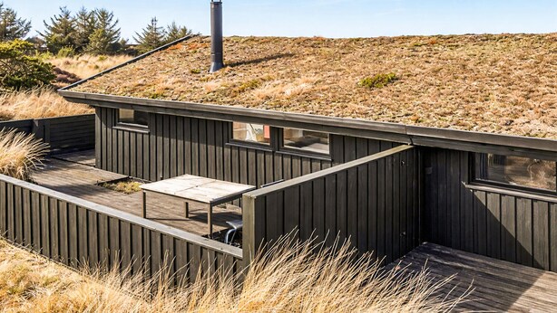 Une structure moderne en bois, dotée d’une terrasse, d’une cheminée et d’une fenêtre.