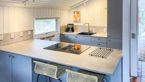 Une cuisine moderne dotée d’un grand îlot central, d’appareils électroménagers intégrés et d’une fenêtre laissant entrer la lumière naturelle.