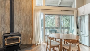 Une cuisine équipée d’une cuisinière intégrée, une table à manger avec des chaises et une vue dégagée sur l’extérieur grâce à de grandes fenêtres.