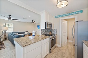 A kitchen with a granite countertop, stainless steel appliances, and a ceiling fan. - Perfect oasis with private pool and wrap around deck! (Port Aransas)