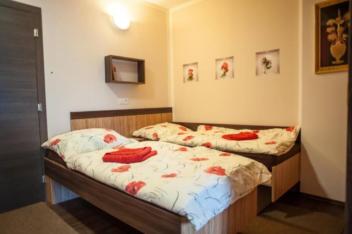 Una cama doble con ropa de cama floral, un estante junto a la cama y tres cuadros en la pared.