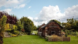 A rustic cabin with a stone exterior, surrounded by a well-maintained garden and a wooden fence. - Luční penzion (Česká Skalice)