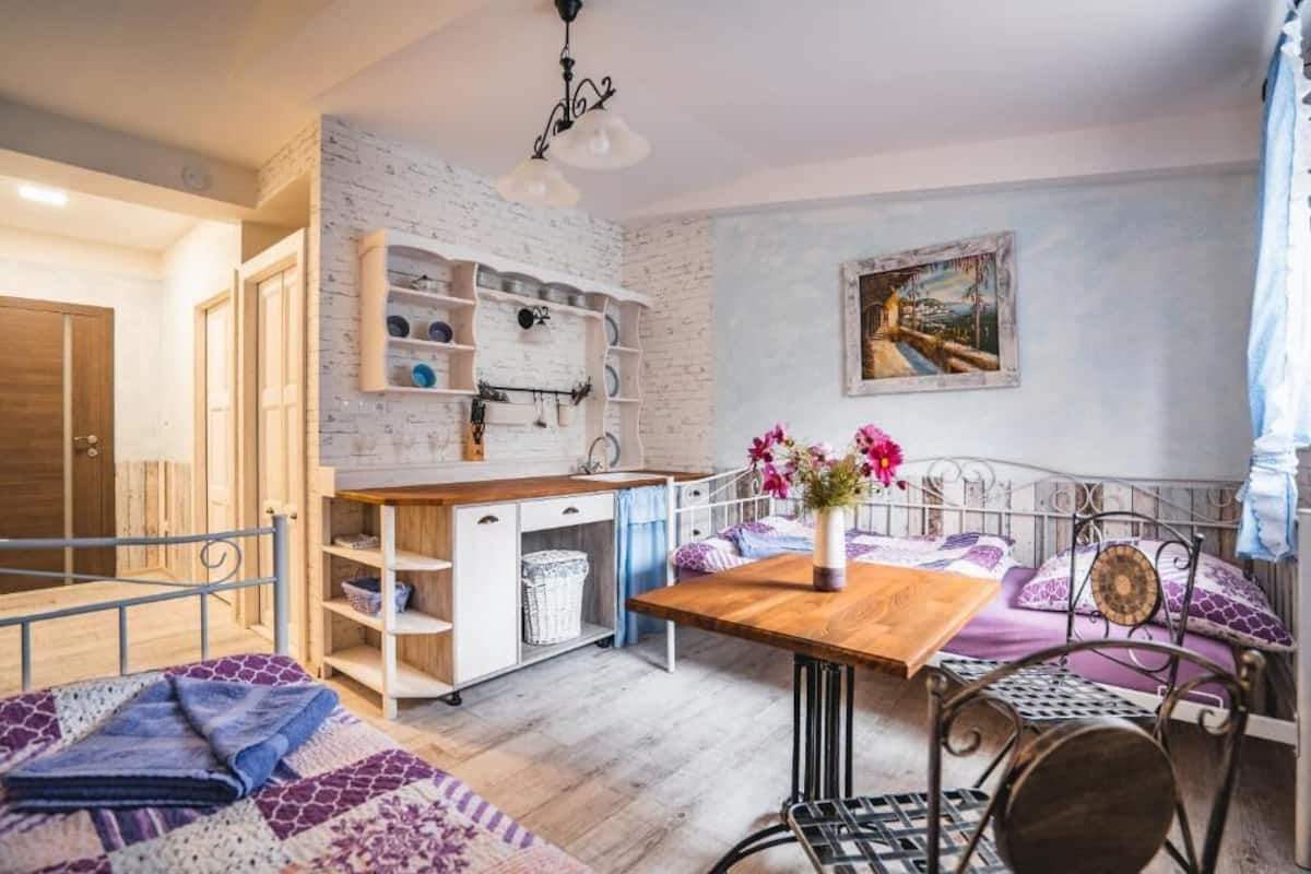Une pièce confortable avec un lit, un bureau et une chaise. On y trouve une étagère avec de la vaisselle et un tableau accroché au mur.