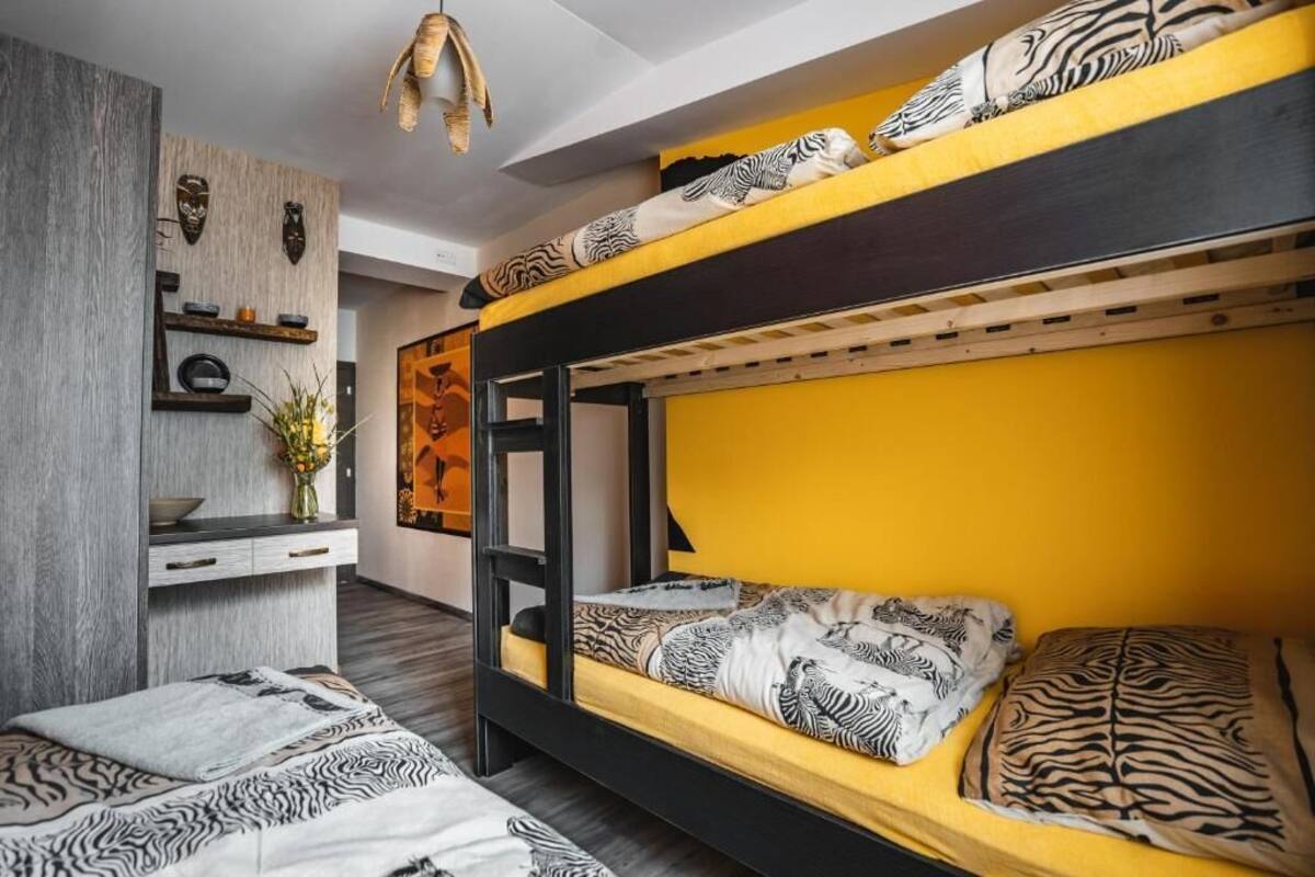 Un lit superposé avec une literie à motifs zébrés, un bureau en bois orné d’un vase de fleurs et une étagère murale décorative.