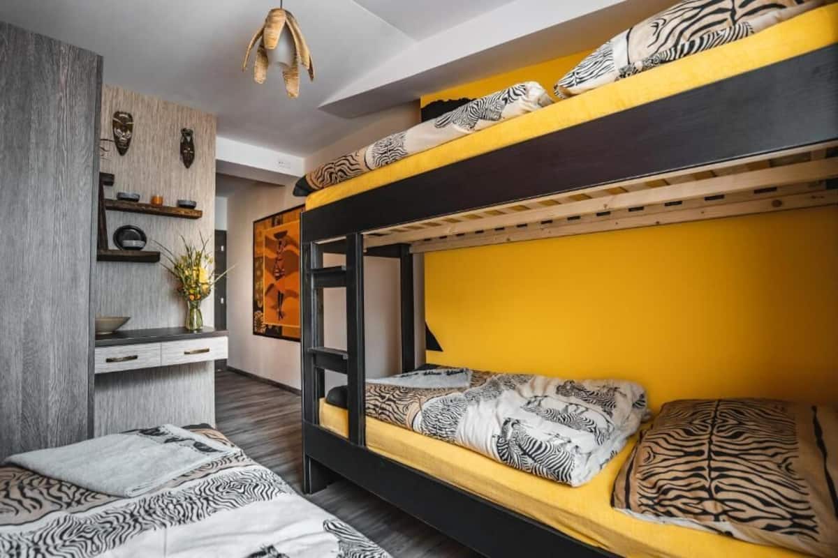 Una cama litera con ropa de cama estampada de cebra, un escritorio de madera con un florero y un estante de pared con objetos decorativos.