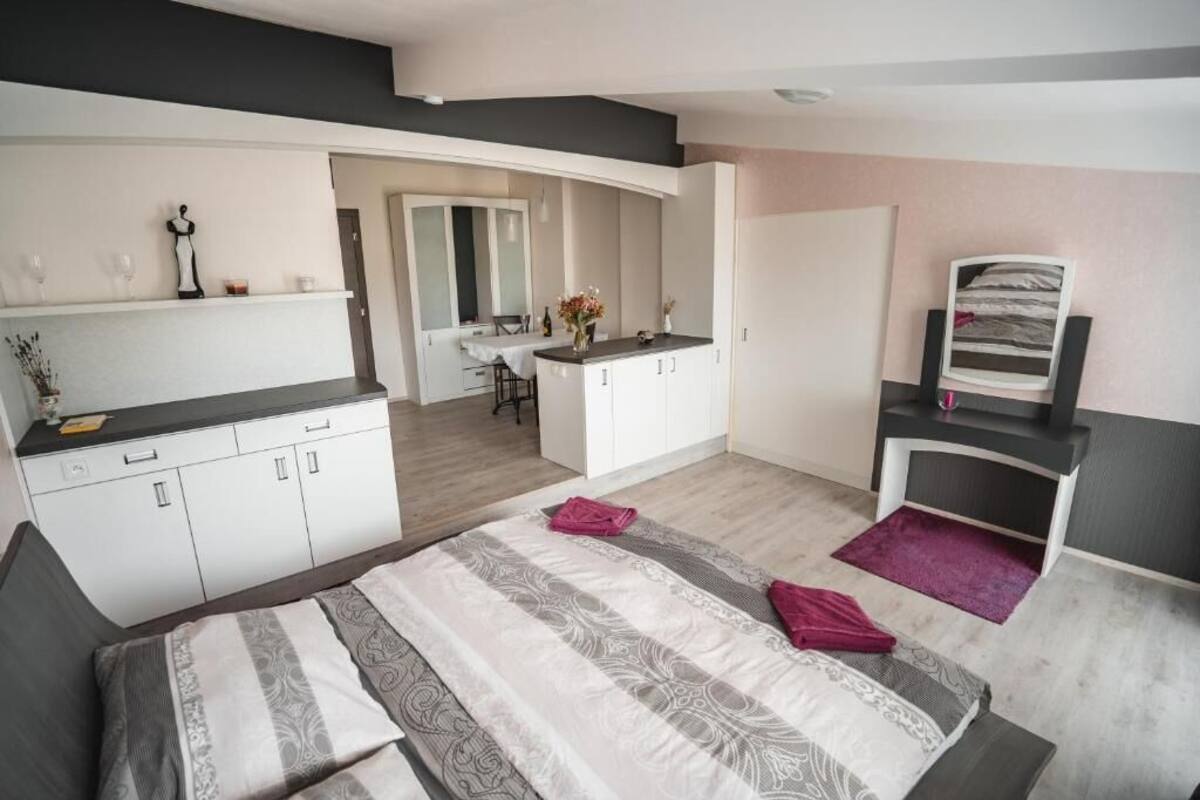 Une chambre moderne avec un grand lit, une coiffeuse avec un miroir et, au fond, un coin repas.