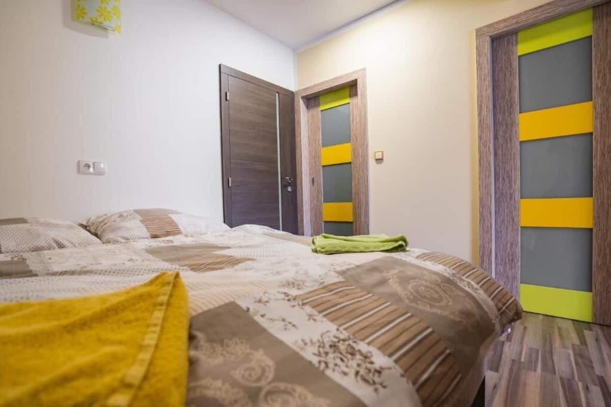 Un dormitorio con cama, dos puertas y un interruptor de luz en la pared.