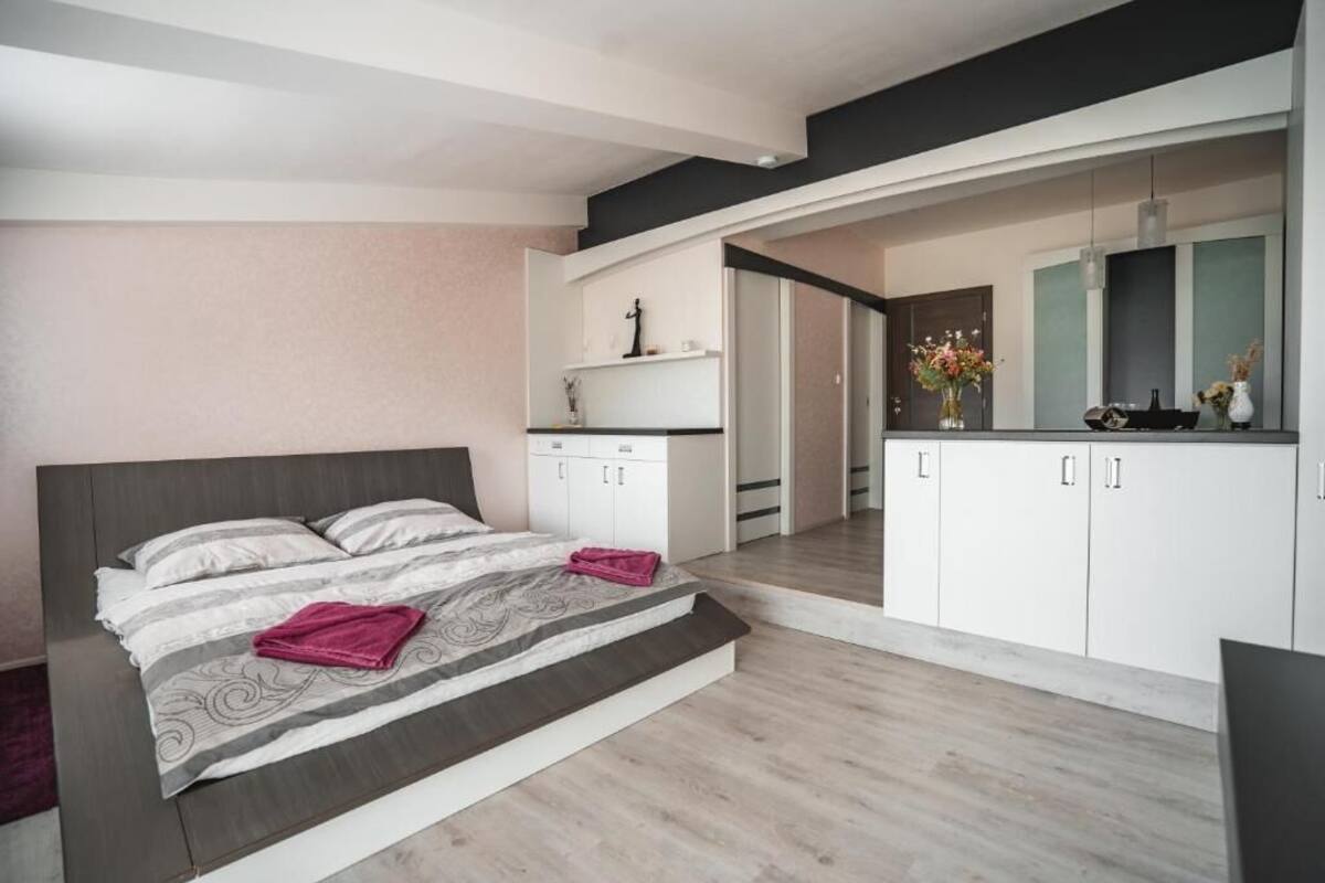 Un dormitorio moderno con una cama, un escritorio pequeño y un baño visible a través de una puerta abierta.