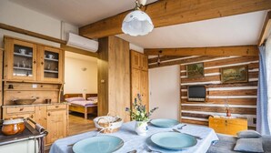 A rustic kitchen with wooden cabinets, a dining table set for four, and a television mounted on the wall. - Luční penzion (Česká Skalice)