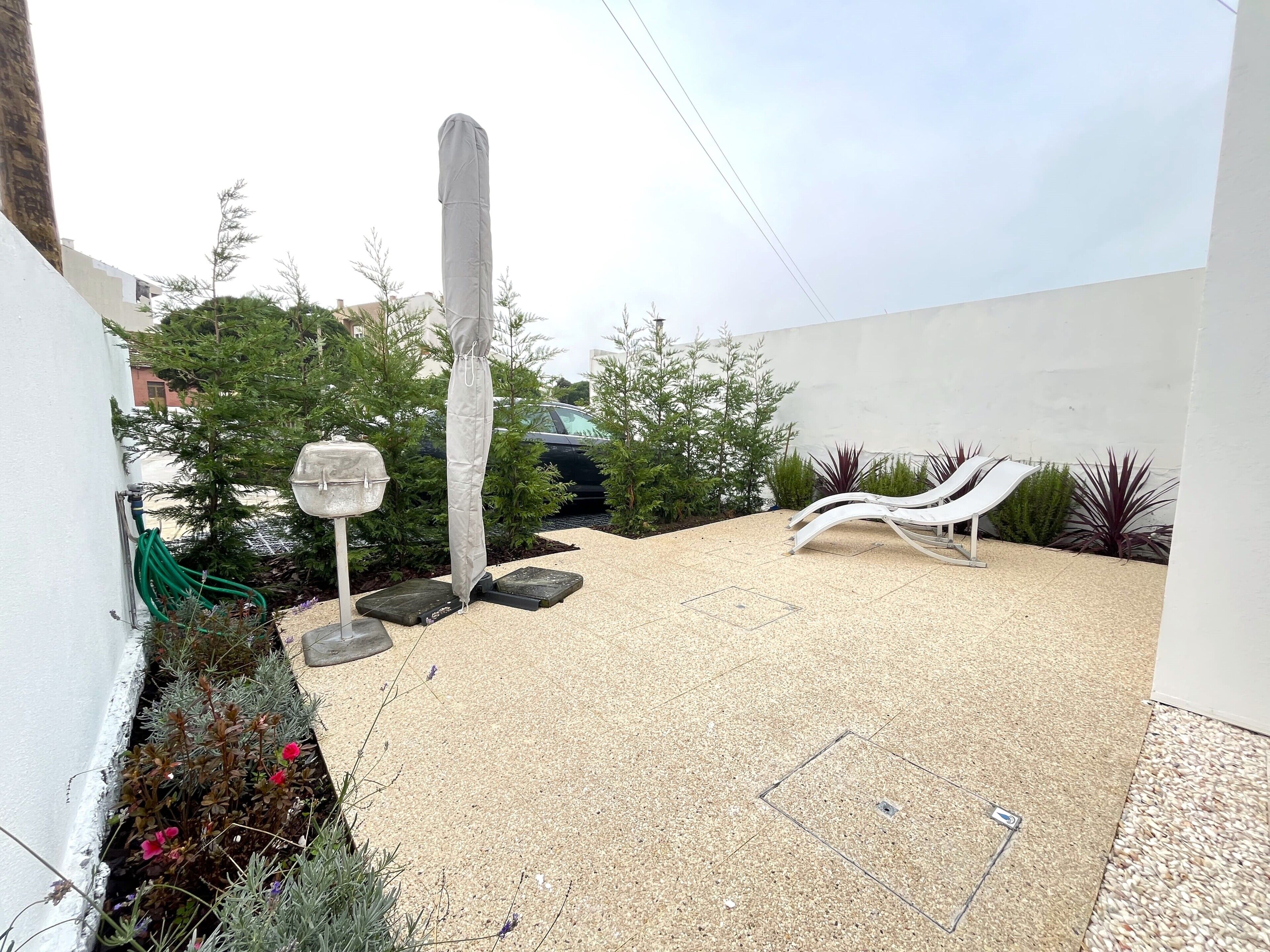 A rooftop garden with a gravel patio, lounge chairs, a water feature, and a covered column.