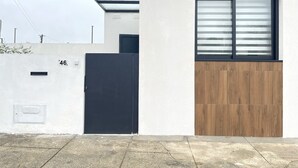 Ein modernes Gebäude mit schwarzem Tor, einer Wand aus Holzpaneelen und einem Fenster mit horizontalen Rollläden.