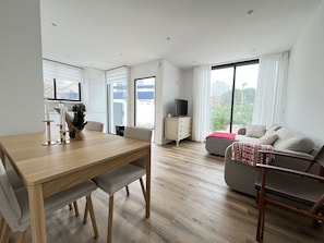 En moderne stue med et træspisebord, en sofa og et fjernsyn på et skab.