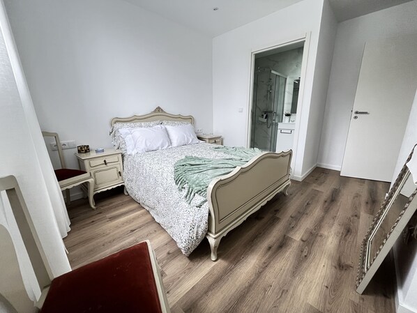 A bedroom with a bed, bedside tables, a chair, a wardrobe, and a bathroom with a shower. - Espinho Beach House by Trip2Portugal (Espinho)