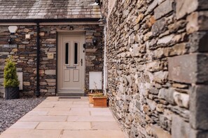 A stone building with a beige door, a small potted plant, and a sign that reads 'Bay Tree.' - Valmere Retreat, Luxury Cottage, Windermere (Windermere)