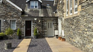 Un bâtiment en pierre avec un toit à pignon, une porte et une petite fenêtre.