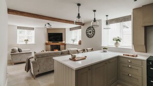 Une cuisine moderne dotée d’un îlot central, de meubles encastrés, de luminaires suspendus et d’une cheminée.