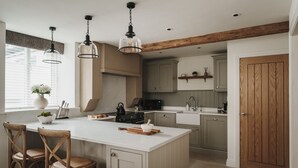 Une cuisine dotée d’un îlot central, de chaises en bois, de luminaires suspendus et d’une porte en bois.